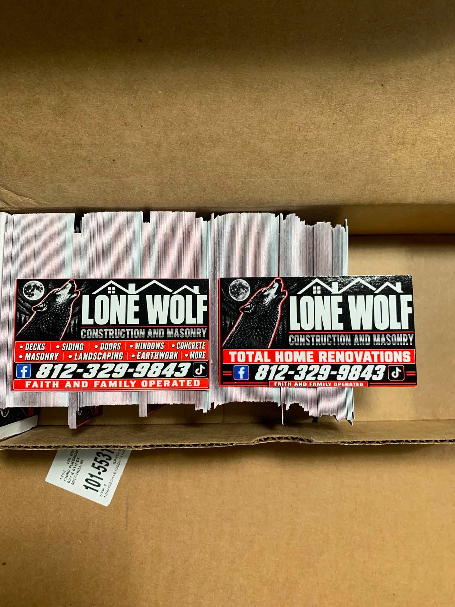 A box of freshly printed Lone Wolf Construction and Masonry decals, two layouts side by side